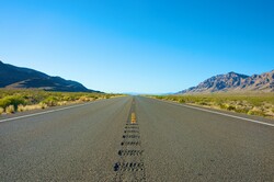 Empty highway runs straight into the heart of Nevada in the American west.