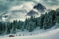 Car traveling in winter landscape in front of mountains