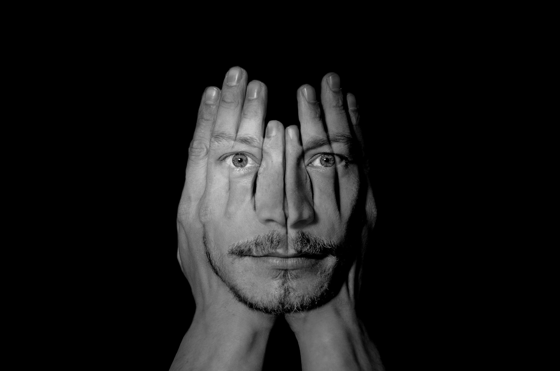 A face in the hands on the black background