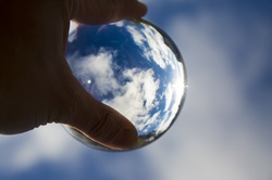 Catching the light - hand holding crystal ball against beautiful blue sky