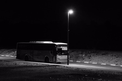 Lonely bus at midnight on street under lamp post