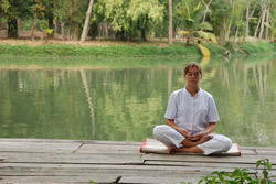 A lady is meditating by the lake in one of the most beautiful monastery in Thailand