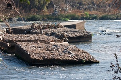 Pieces of pipe embedded in broken up concrete blocks in a river