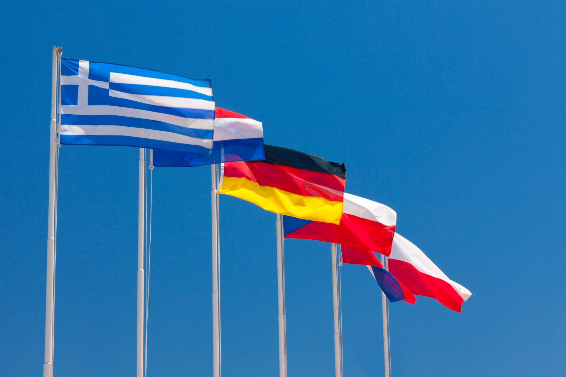 Several national flags against blue sky