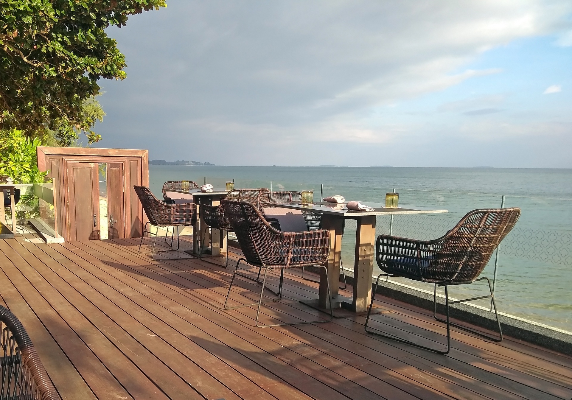 Restaurant Table and Chairs on Wooden Decking with View of Beach and Ocean