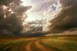 Fantastic landscape with storm clouds and the road into the field