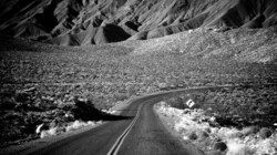 Narrow two lane road winds through the brush of the Mojave Desert in southern California.