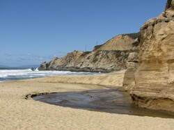 The ocean cuts into the sand to create this inlet of water at the beach in Northern California