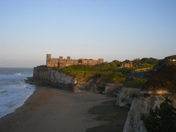 Castle by cliffs with green shrubby trees and sea view