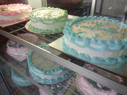 Many pastel colored birthday cakes in display case