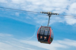 Black cable car against blue sky with white clouds