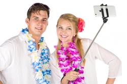 Vacation couple taking selfie with a selfie stick isolated on white background