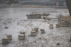 A small boat frozen in place on pond