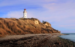 Lighthouse standing tall and focused on a point of coastal land.