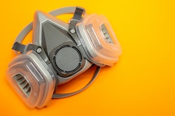 Face mask on orange background with copy space