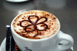 A cup of cappuccino coffee with a flower