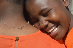 An African girl laughing at the shoulder of her friend.