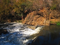 Hennops river cascading over a weir and flowing downstream