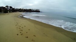 Wide angle shot of small waves breaking against the smooth wet sand