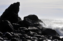 Waves breaking on rocks silhouetted in afternoon sun