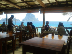 People having dinner with a beautiful island and sea view behind them