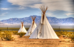 Three teepees in desert setting