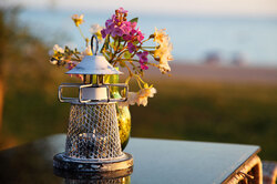 Candle holder and flowers on restaurant table with ocean view