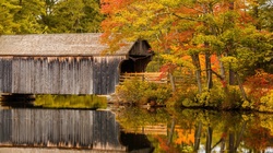 Old wooden covered bridge with the pond reflection in autumn