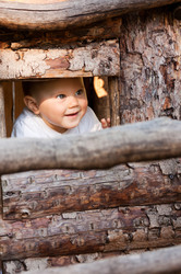 Small baby boy playing peekaboo in a wooden house