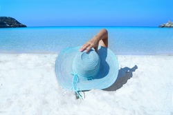Woman resting on the beach with a blue hat