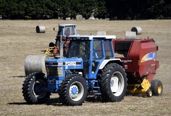 Tractor moving bales of hay to be sold to feed livestock.