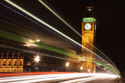 Big Ben at night with light trails caused by two double deckers passing by