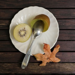 Half kiwi fruit on white plate with a spoon
