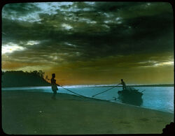 Two men landing boat on beach.