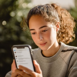 Person interacts with a digital display, receiving notifications on a handheld device