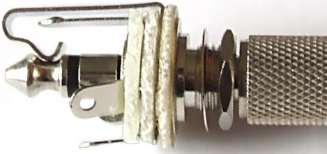 Phone plug mated in a phone socket. The plug's grooved tip is held firmly by the socket's spring tip contact. When not mated, this spring instead connects to the flat switch contact for detecting a plug.