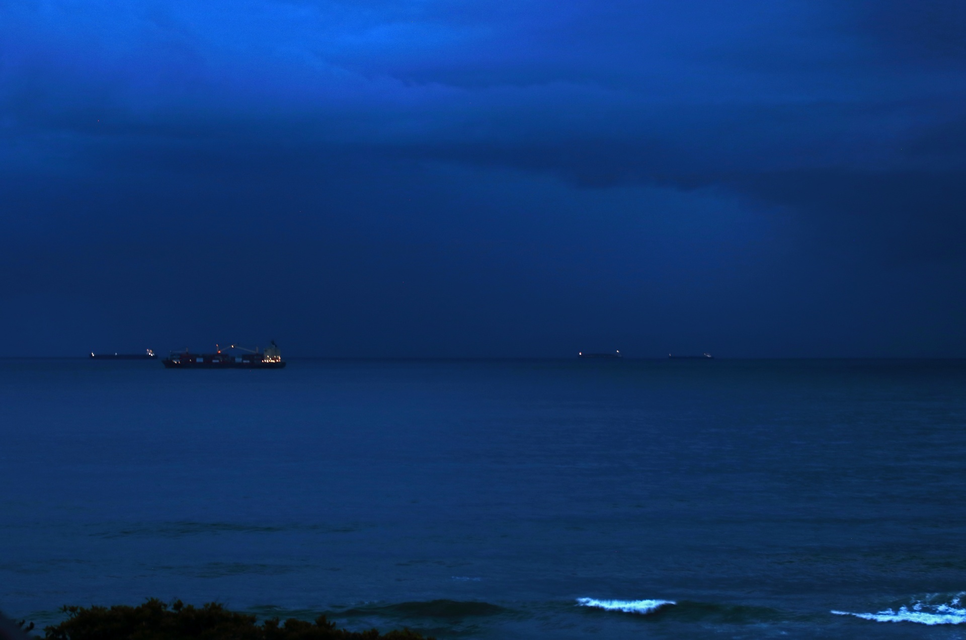 CARGO VESSELS AT SEA WITH LIGHTS ON AT DUSK