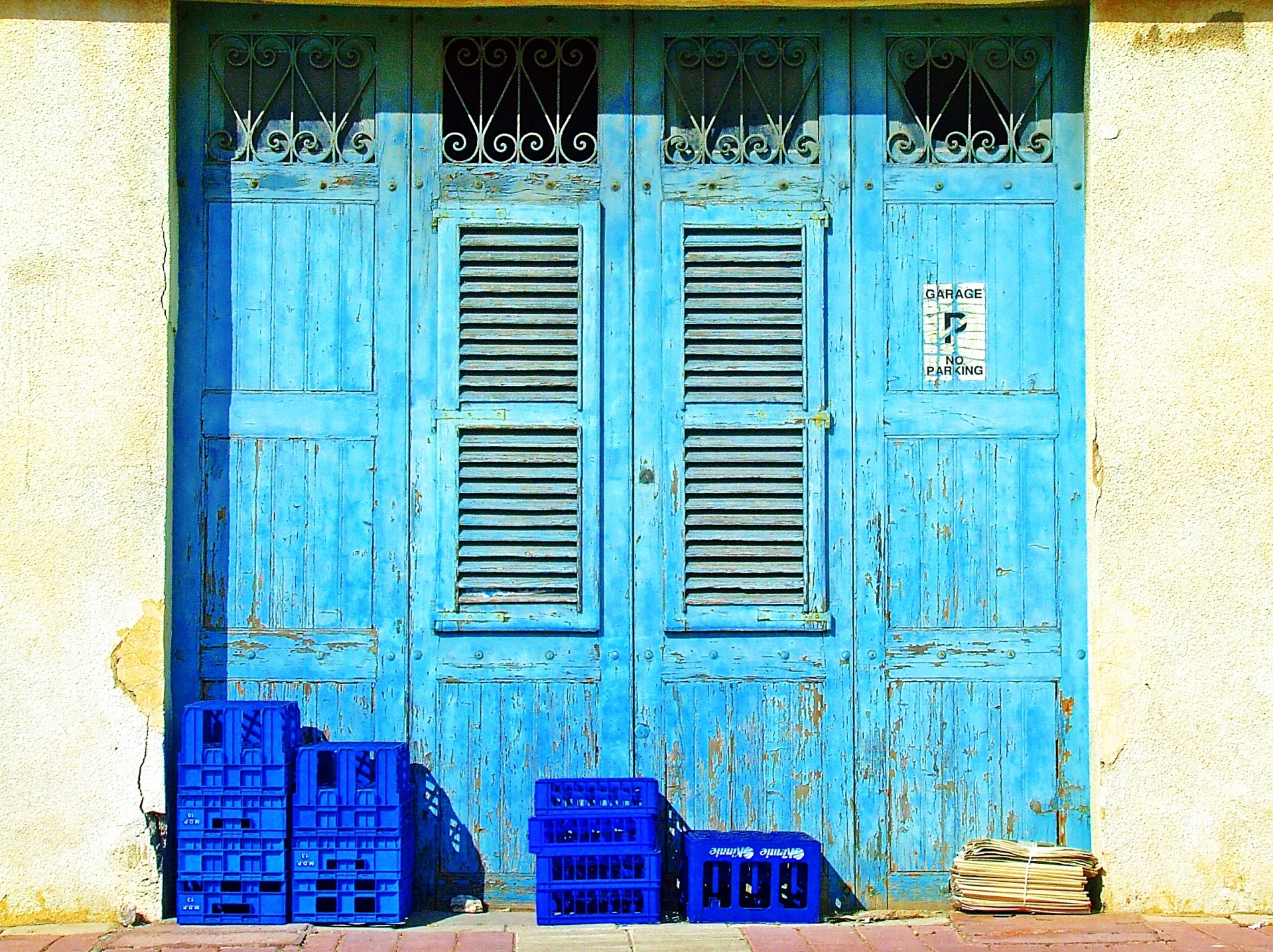 Old weathered blue doors, blue crates and newspapers outside of a small village shop in Malta