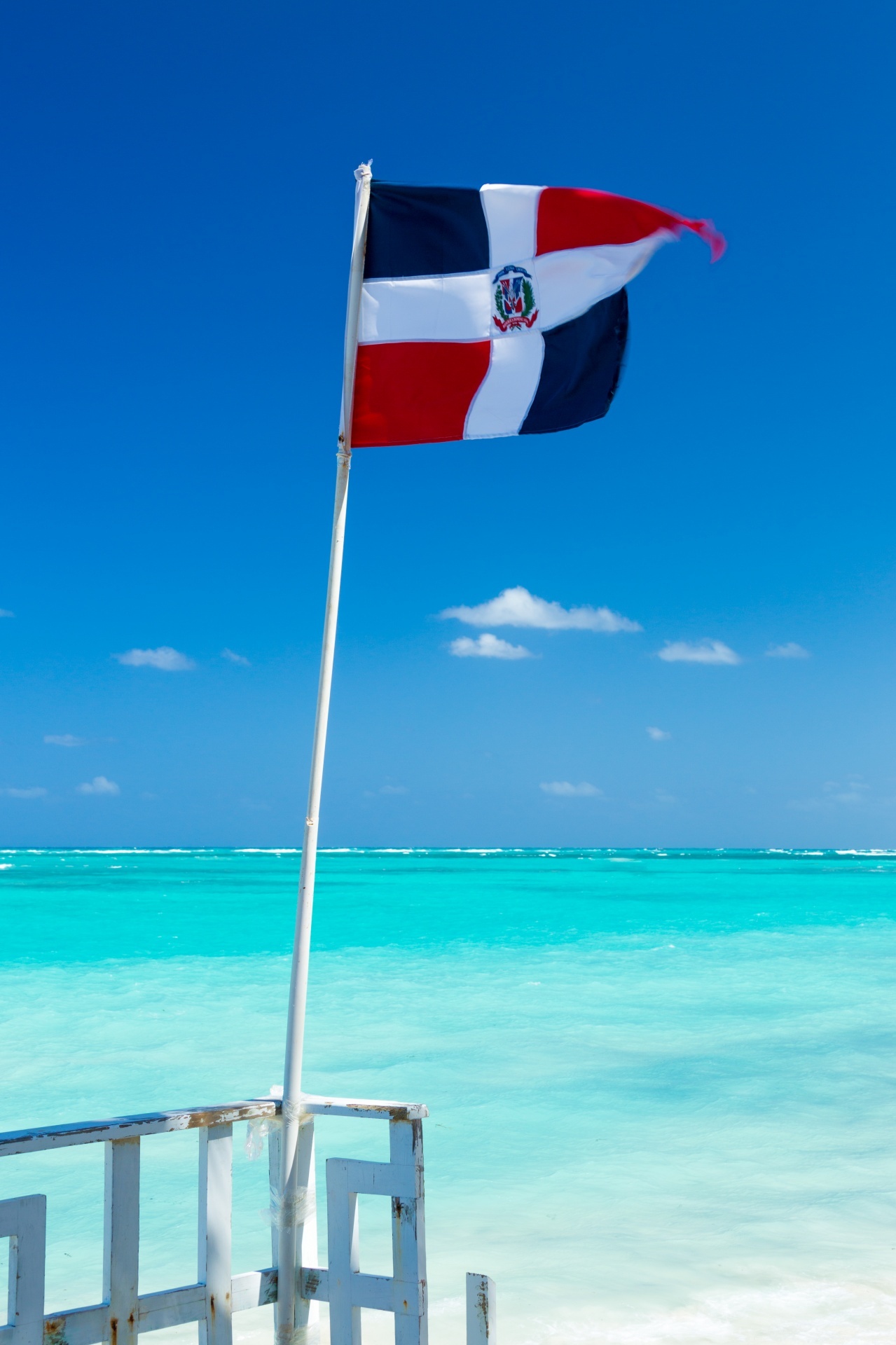 Dominican republic flag against blue sky and the sea in the background/