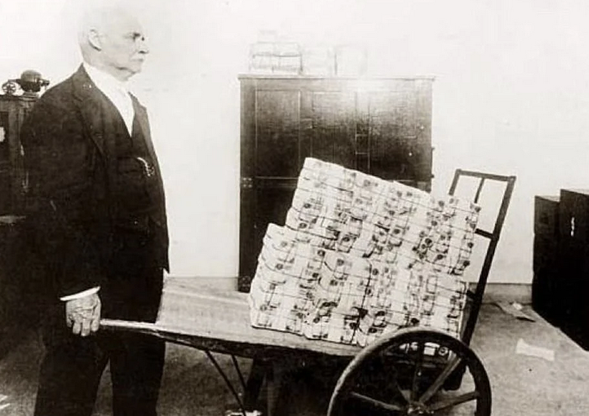 A man carrying a wheelbarrow full of cash, which effectively became people's wallets due to hyperinflation in 1923 in Germany