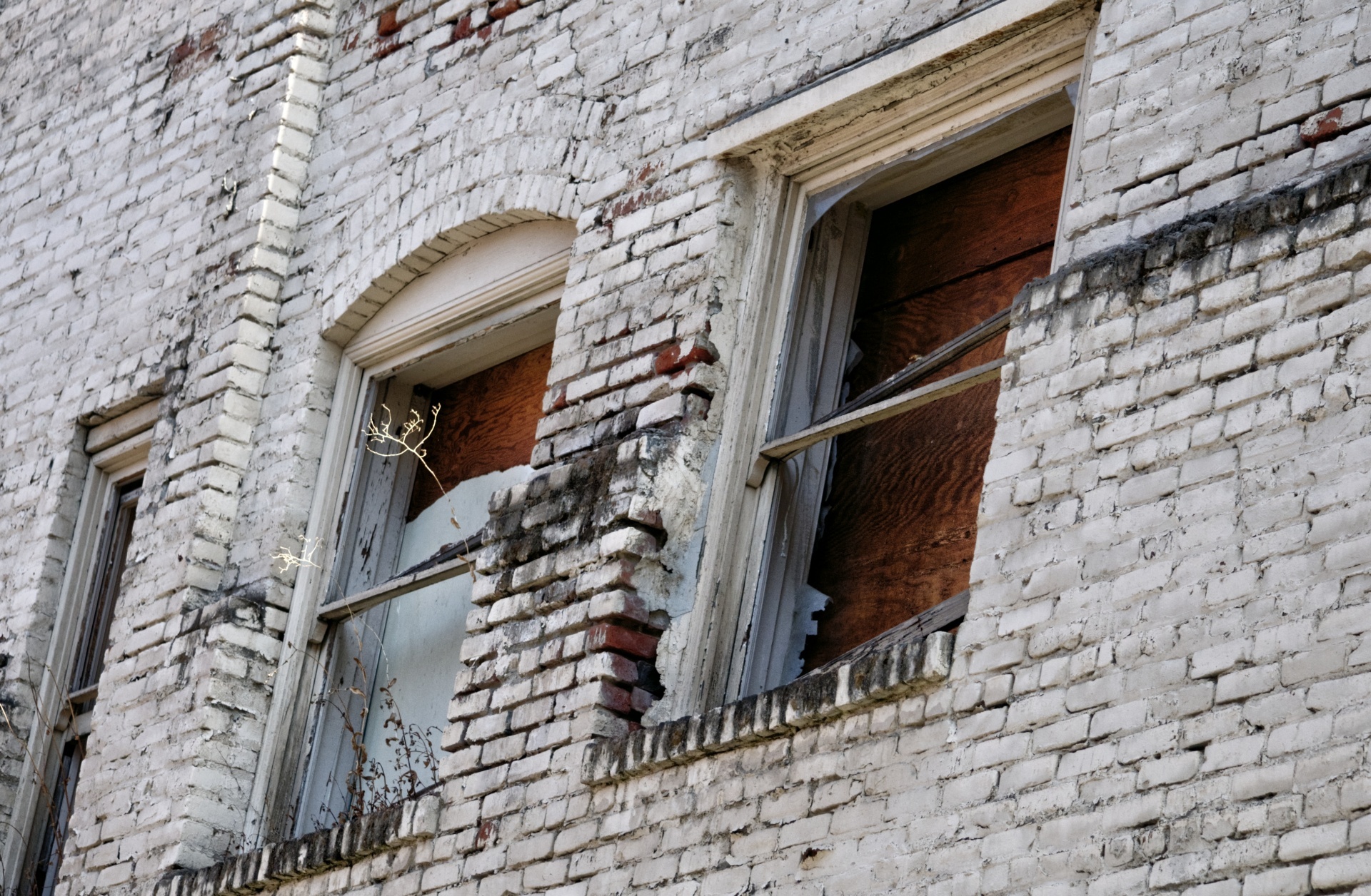 Three broken boarded up windows in old brick building