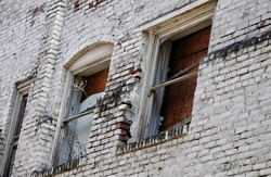 Three broken boarded up windows in old brick building