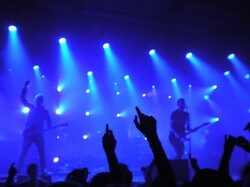Live rock concert performance with hands in the air silhouette blue lights and crowd