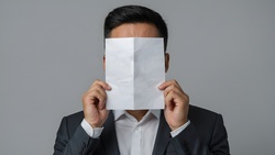Businessman hiding behind blank sheet of paper