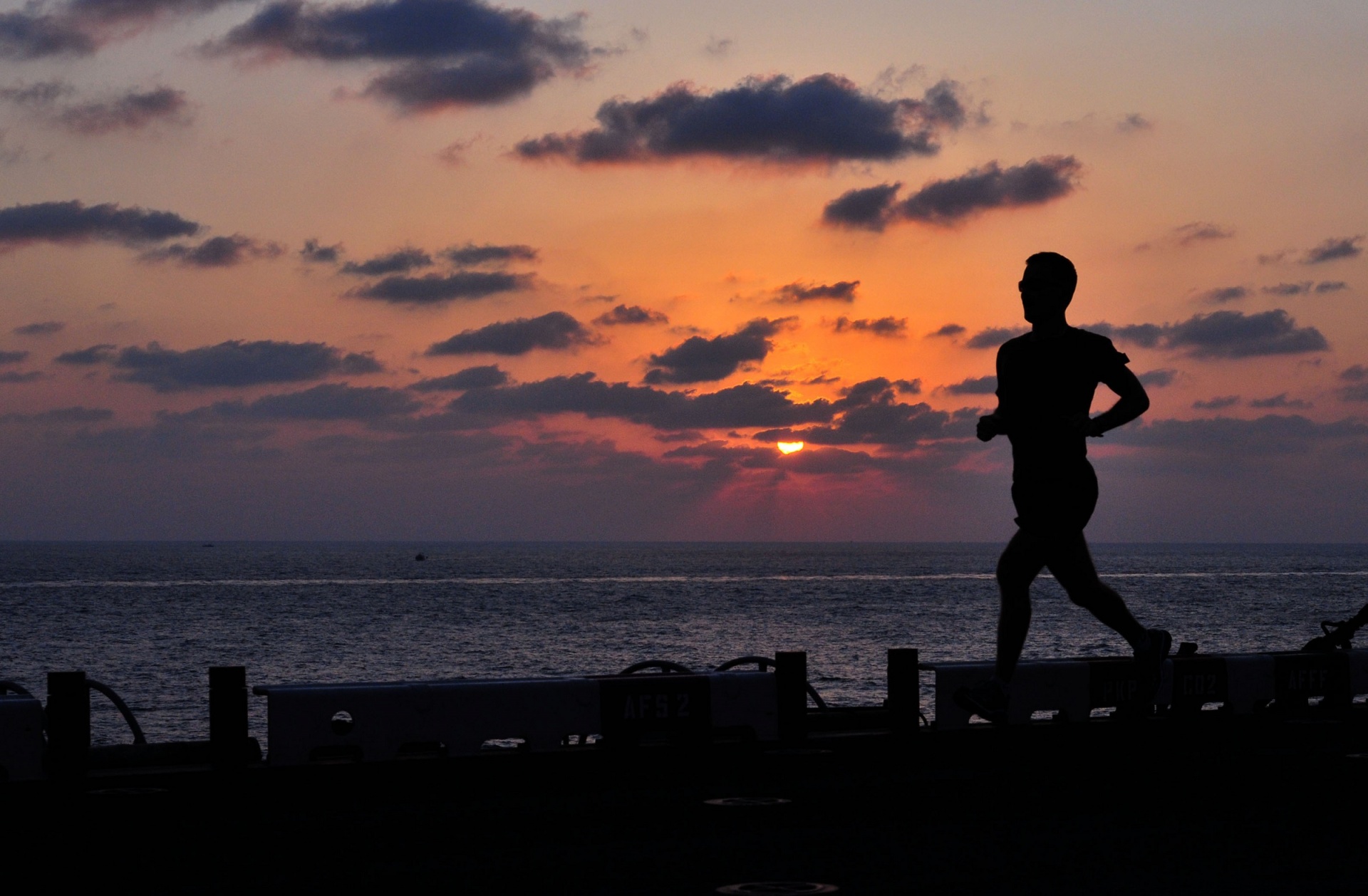 Sailor jogs at sunset on the flight deck of his navy ship