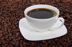 Cup of coffee surrounded with coffee beans