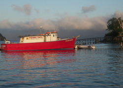 Photo of a deep sea fishing boat with dark storm clouds approaching