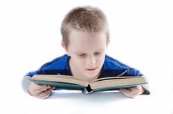 Small boy reading a book on a white background