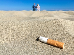 A cigarette butt left by people in the distance on the beach