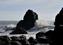 Waves breaking on rocks silhouetted in afternoon sun